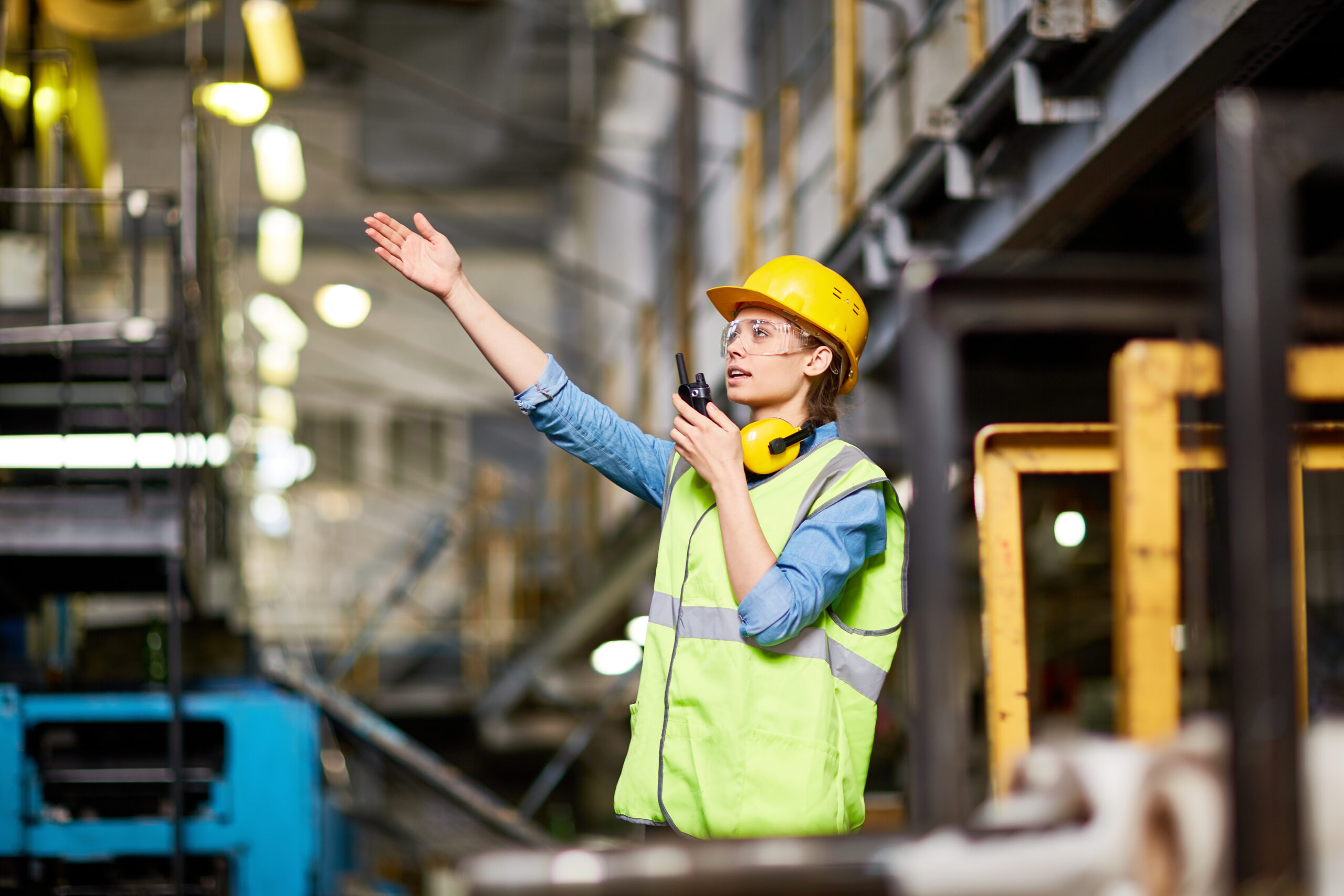 Young female engineer talking on walkie talkie at factory